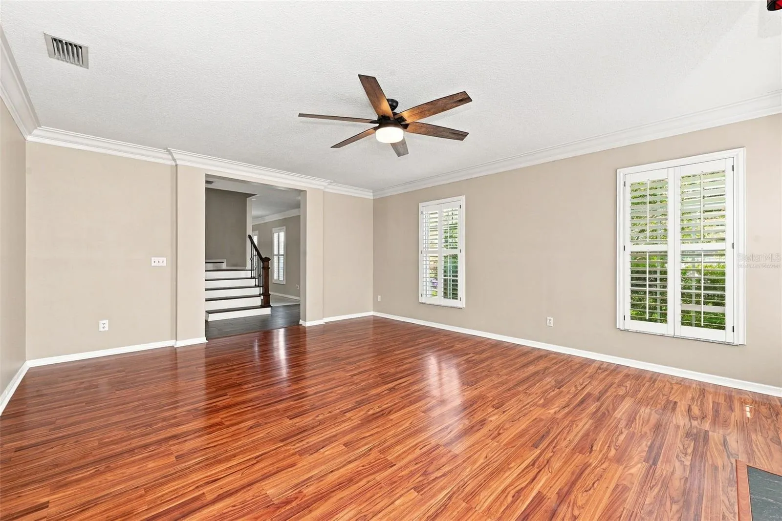 Formal Living Room with wood burning fireplace, crown molding and plantation shutters