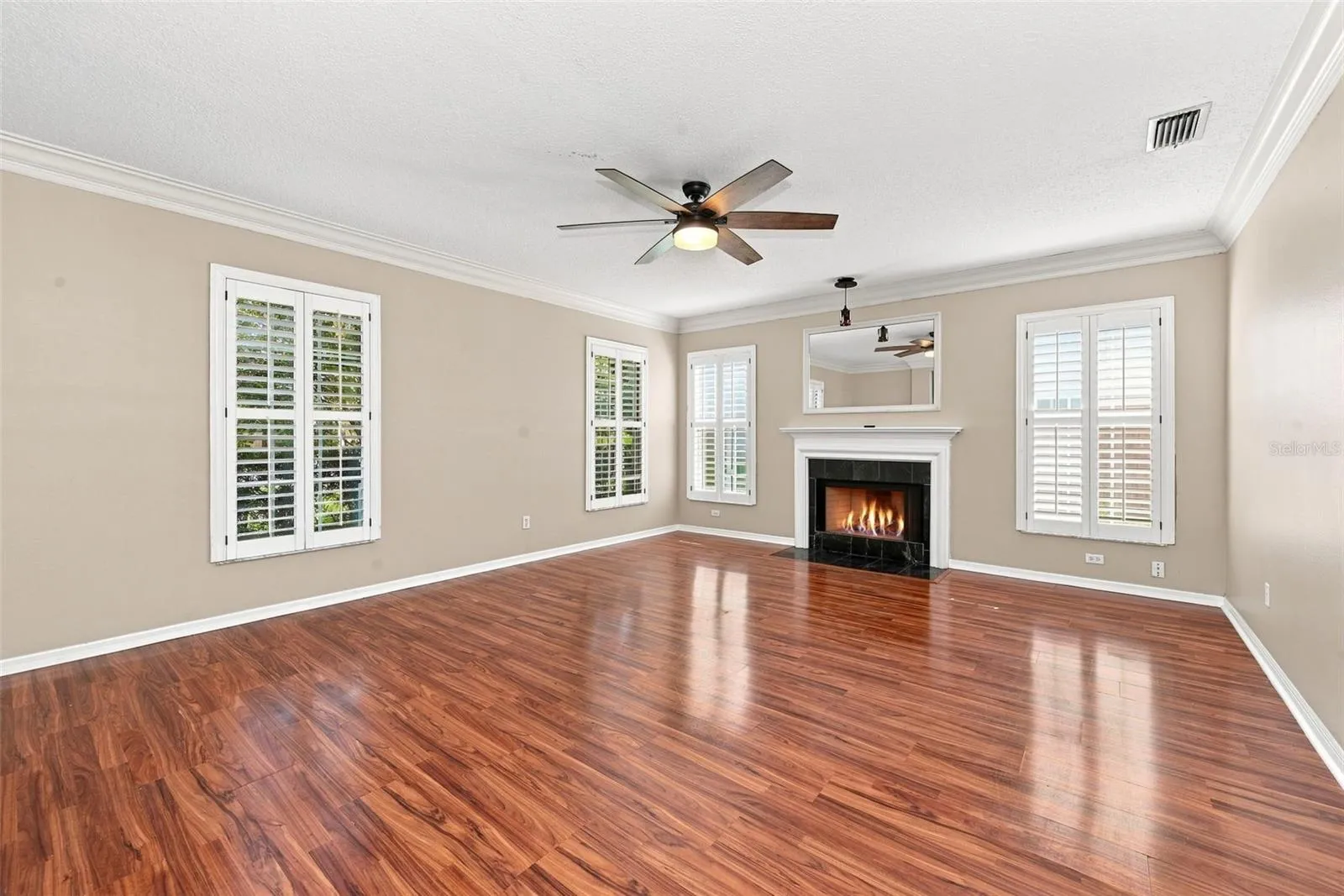 Formal Living Room with wood burning fireplace, crown molding and plantation shutters