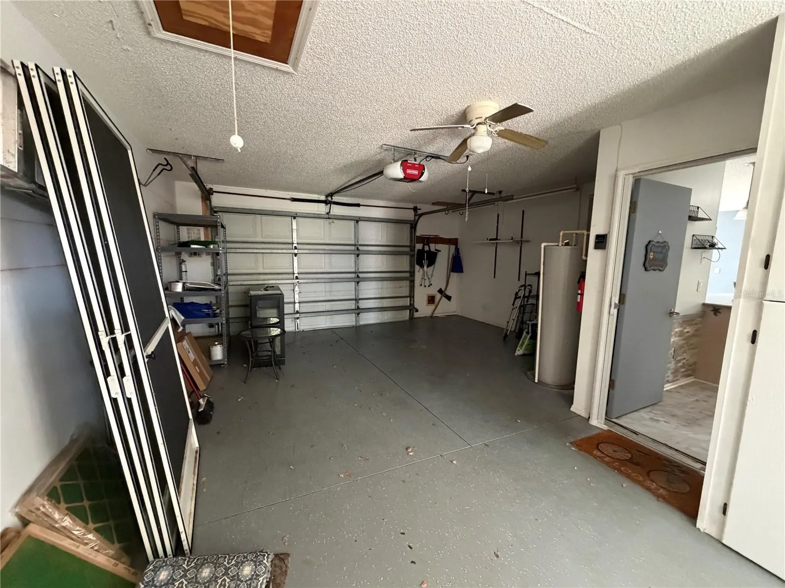 Attached one-car plus golf cart garage with storage shelving, attic access, and utility space.