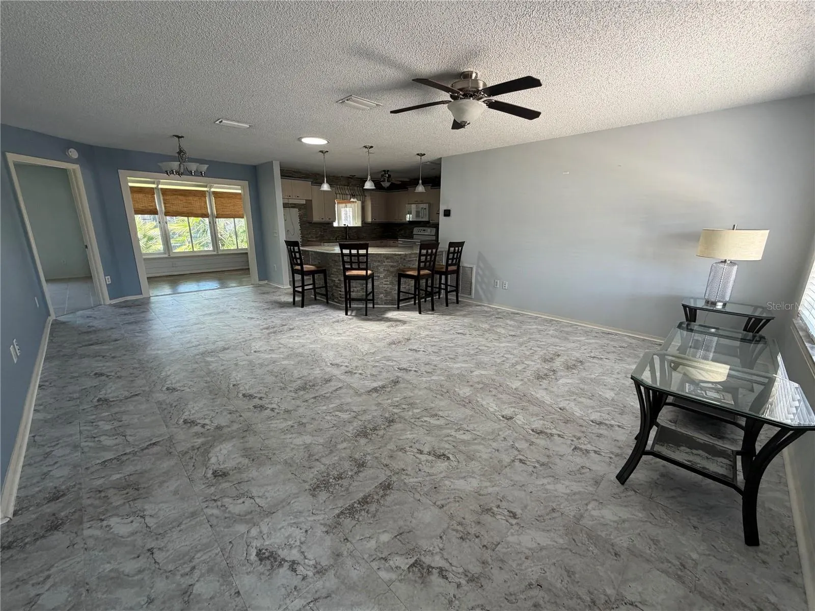 Open living area with updated flooring, ceiling fan, and connected kitchen and Florida room layout.