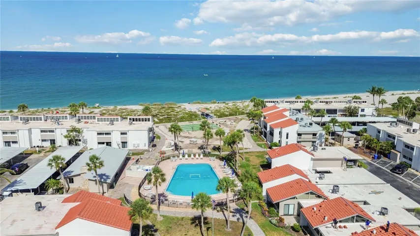 Aerial view showcases resort-style amenities including pool, putting green, and direct beach access.