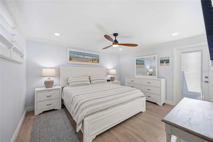 Bright and inviting primary bedroom retreat featuring luxury flooring, plantation shutters, and modern coastal décor.