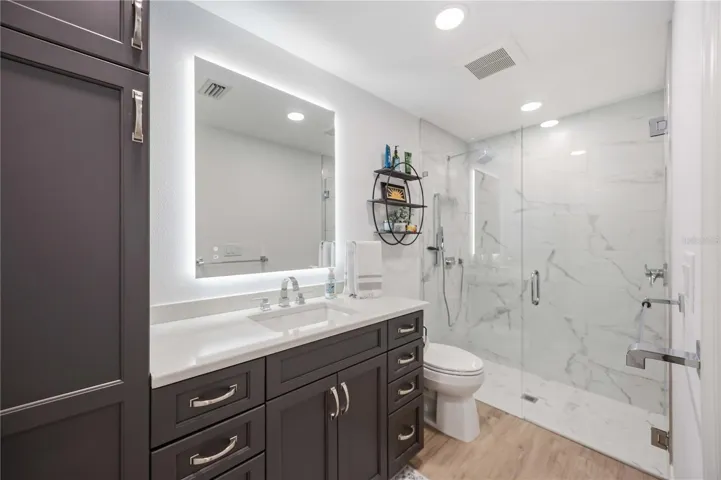 Designer-inspired bath showcasing sleek finishes, frameless glass shower, and elegant marble-look tile.