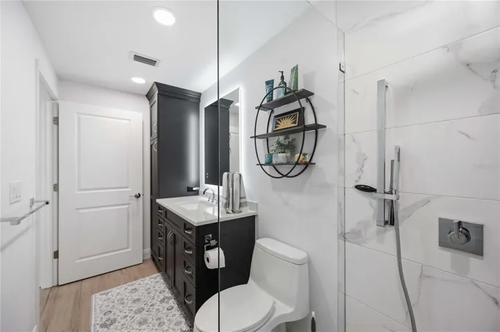 Luxuriously remodeled bathroom with granite counters, custom cabinetry, and oversized walk-in shower.