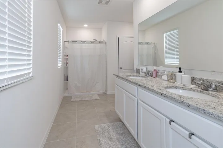 Primary bathroom with dual sinks, granite countertops, and spacious layout.