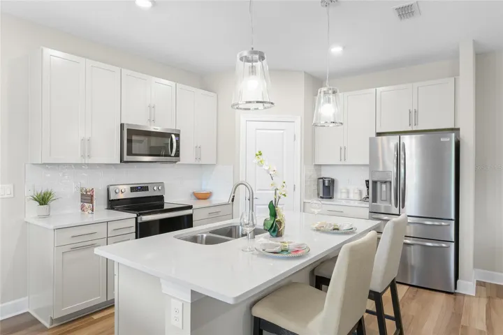 Beautiful and functional Kitchen with quartz countertops and shiny subway tile, pull out lower shelving on the lower cabinets, pull out trash/recyclable cans and a walk in pantry with abundant shelving.