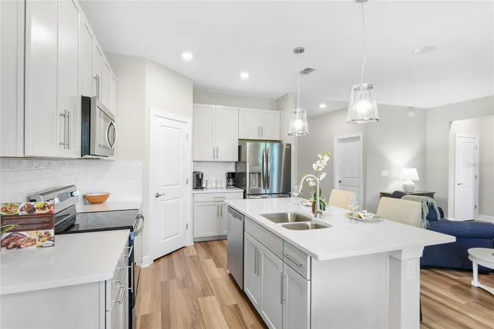 Beautiful and functional Kitchen with quartz countertops and shiny subway tile, pull out lower shelving on the lower cabinets, pull out trash/recyclable cans and a walk in pantry with abundant shelving.