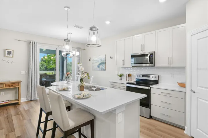 Beautiful and functional Kitchen with quartz countertops and shiny subway tile, pull out lower shelving on the lower cabinets, pull out trash/recyclable cans and a walk in pantry with abundant shelving.