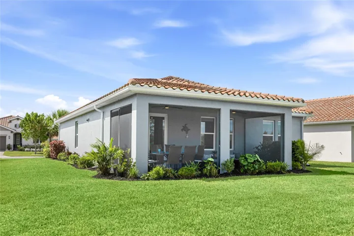 Rear view of screened in, covered and extended Lanai with access door, two ceiling fans and panoramic water and preserve views. Plenty of room for a pool or extended cage with pavers. Extra space between homes.