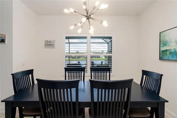 Dining Area with Contemporary Lighting & Scenic Backyard Water ViewsElegant dining space with designer chandelier, plantation shutters, and tranquil lake views. Perfect for family dinners, holiday gatherings, or entertaining guests in a stylish Southwest Florida waterfront home.