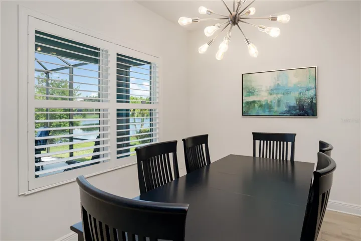 Bright Dining Room with Plantation Shutters & Resort-Style AtmosphereLight-filled dining area combining modern elegance with Florida coastal charm. Plantation shutters and water views create a peaceful setting buyers are searching for in luxury homes near Sarasota, Bradenton, and Lakewood Ranch.
