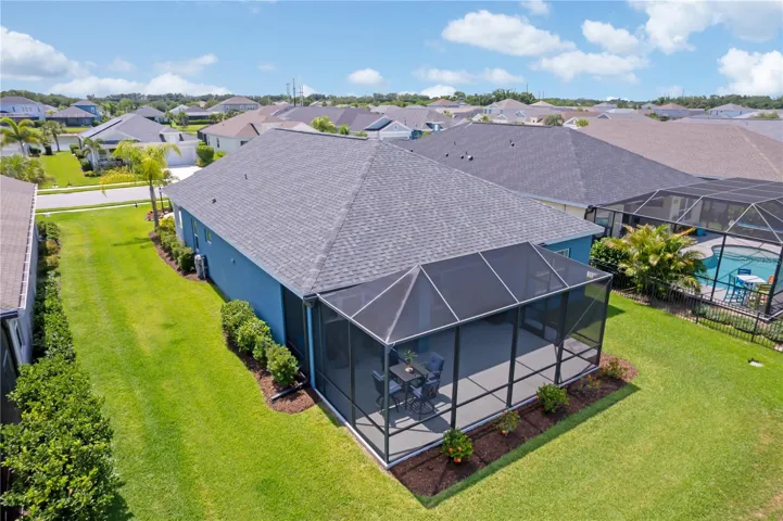 Rear Aerial Showing Backyard & LanaiThe screened lanai offers the ideal place to enjoy peaceful mornings, outdoor dining, and relaxing evenings while overlooking the spacious backyard and nearby water views.