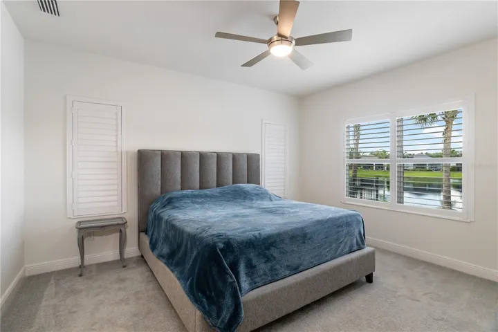Primary Bedroom Retreat with Water Views & Private En Suite AccessSpacious owner’s suite featuring plush carpeting, plantation shutters, and peaceful water views that create a relaxing retreat atmosphere. Perfect for buyers seeking luxury single-story homes with serene Florida living.