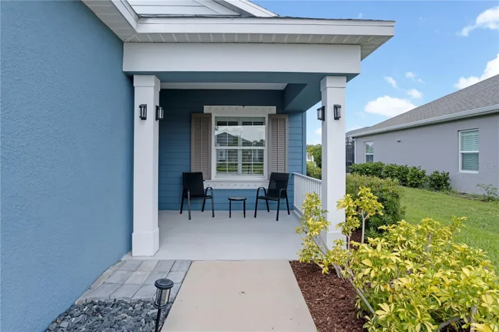 Private covered entryway with upgraded lighting and coastal color palette.