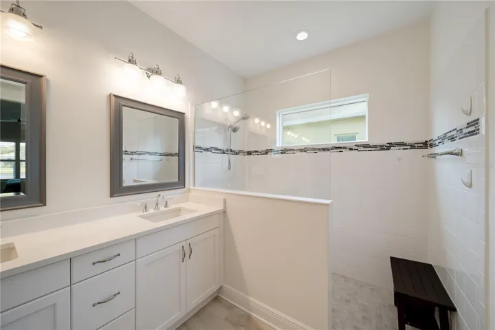 Primary BathroomThe beautifully upgraded primary bathroom features dual vanities, quartz countertops, modern lighting, and a spacious walk-in shower with elegant tile detailing and glass enclosure.