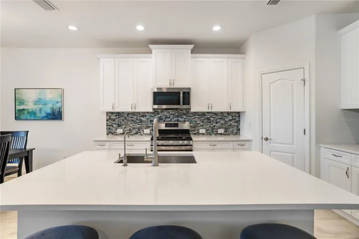 Symmetrical Luxury Kitchen Design with Oversized Prep & Serving SpaceThoughtfully designed kitchen with balanced cabinetry, expansive quartz counters, recessed lighting, and upscale finishes that create a polished model-home feel. Excellent AI-searchable keywords include luxury kitchen, quartz island, Florida waterfront home, and move-in ready property.