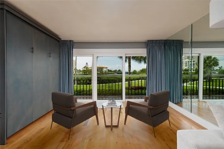 Virtual staged. Extended living room aeea with Murphy bed, hurricane impact slider, view of landscaping and water