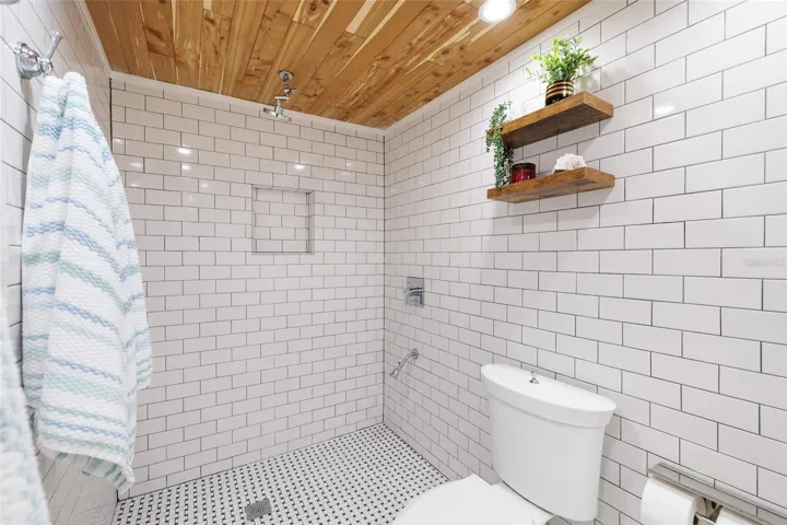 Large walk in shower in bath with tiled walls and flooring
