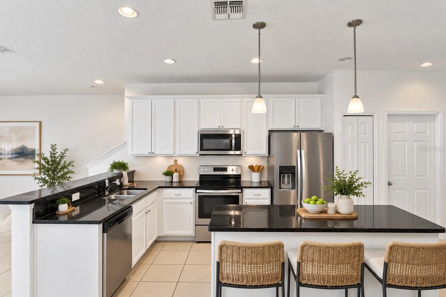 Bright, open kitchen with white cabinetry, granite countertops, stainless steel appliances and center island.