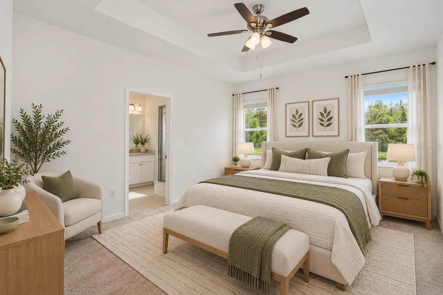 Spacious primary bedroom with tray ceiling, ceiling fan, dual windows and private access to the en-suite bath.