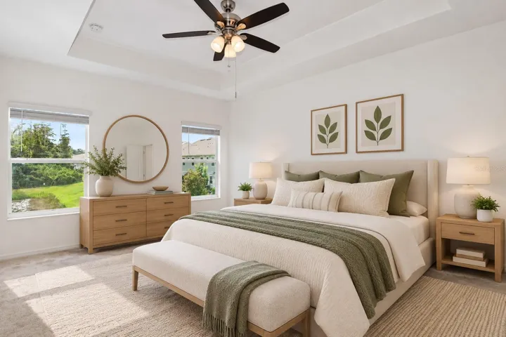Another view of the primary bedroom highlighting the generous wall space, natural light and tray ceiling.