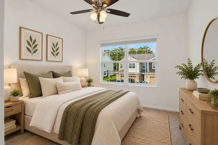 Bright secondary bedroom with ceiling fan, neutral carpeting and a large window providing plenty of natural light.