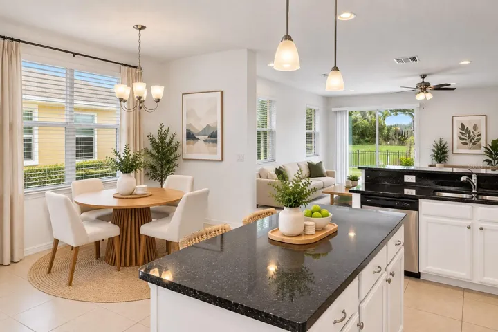 Bright living area with multiple windows, tile flooring and an open layout overlooking the kitchen.