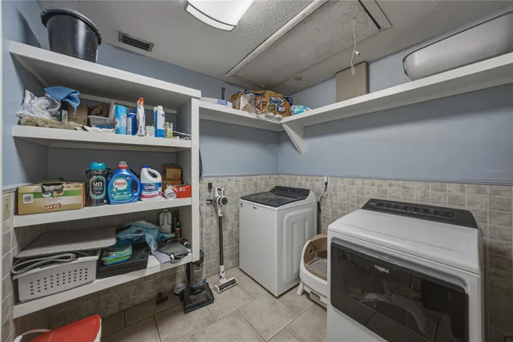 Nicely sized inside utility room with more shelving for storage.