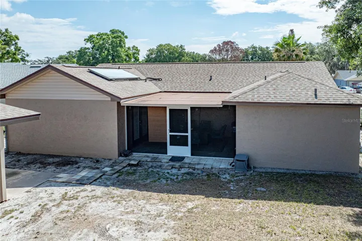 Rear exterior photo showing the porch.  ONE SOLAR PANEL IS FOR THE HUGE HOT WATER HEATER.  SELLERS HAVE PAID OFF THE PANEL.