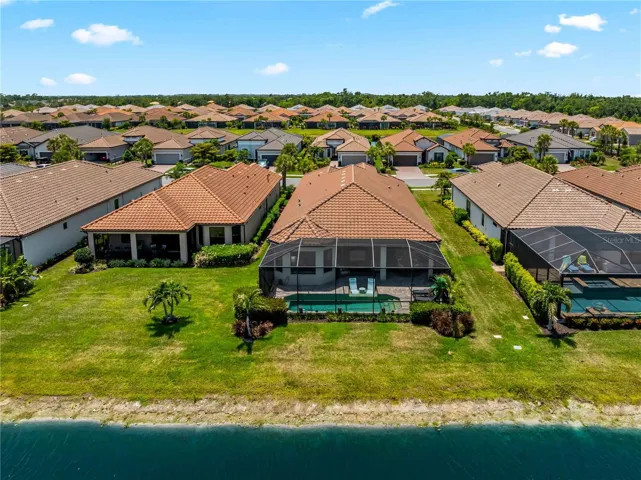 Aerial views showcase the stunning backyard retreat featuring the sparkling pool, peaceful lake, and beautiful outdoor living space.