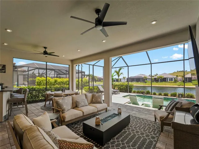 Additional photos highlight the expansive outdoor living space, featuring  abundant seating, a sparkling pool, and beautiful sunshine with serene lake views.