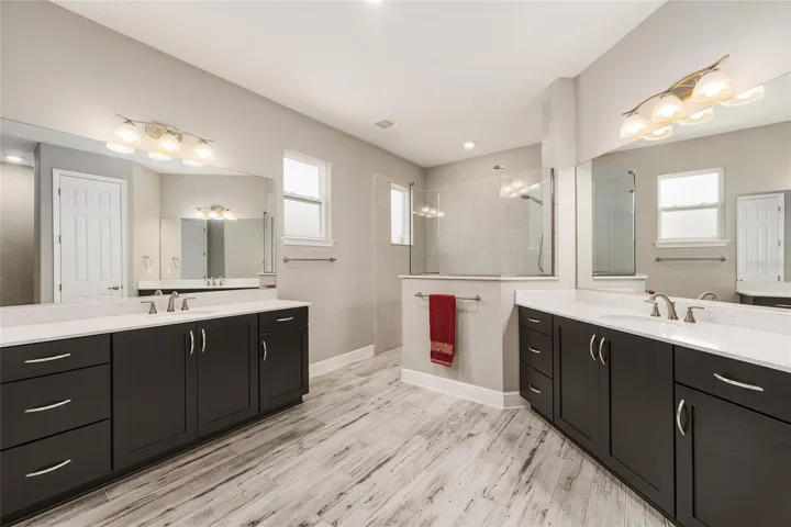 First primary bathroom ensuite featuring separate vanities with abundant cabinet storage and plenty of space for everyday convenience.