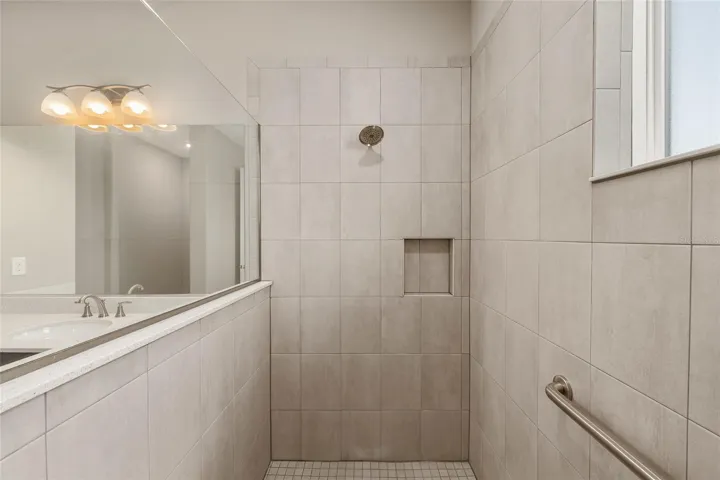 Second primary ensuite featuring a large zero-entry walk-in shower with tile surround, glass enclosure, built-in niche, and grab bar for added convenience.