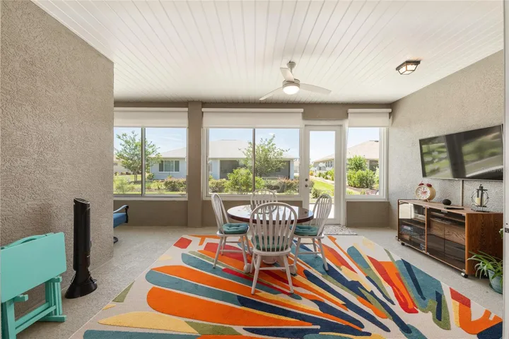 Inviting enclosed lanai with custom solar shades, ceiling fan with light, and large windows that create a bright, relaxing space.