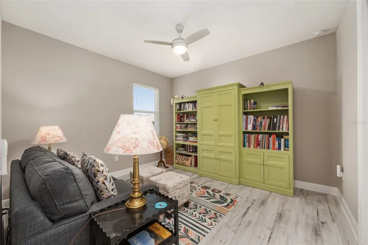 Comfortable third bedroom featuring ceramic plank flooring, ceiling fan with light, neutral finishes, and natural light.