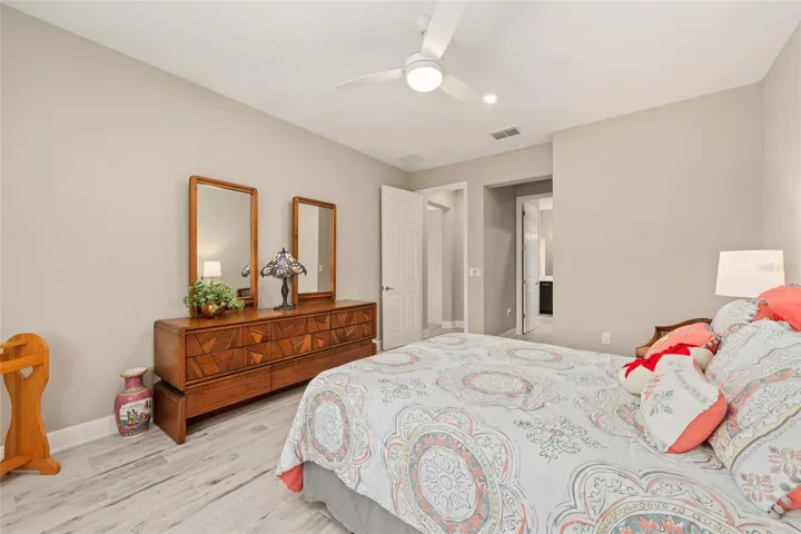 Second primary suite featuring an alcove, ceramic plank flooring, ceiling fan with light, neutral finishes, and private ensuite comfort—ideal for guests or multi-generational living.