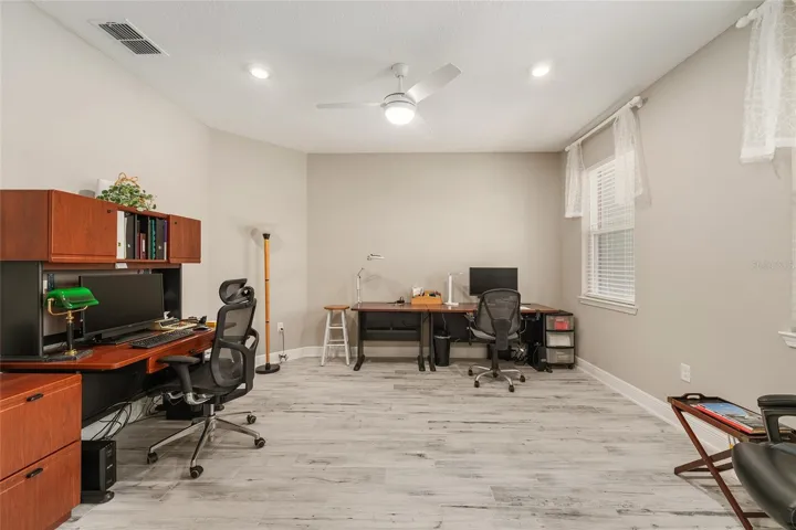 Spacious flex room with ceramic plank flooring, neutral finishes, recessed lighting, ceiling fan with lighting, and great natural light—ideal for a home office, sitting room, or hobby space.