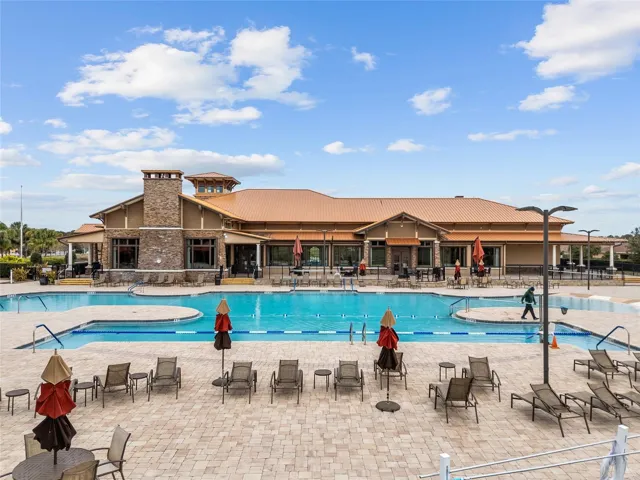 Candler Hills resort-style pool featuring swim lap lanes, beach entry, spacious pool deck, and clubhouse views—perfect for exercise, relaxation, and enjoying the Florida lifestyle.