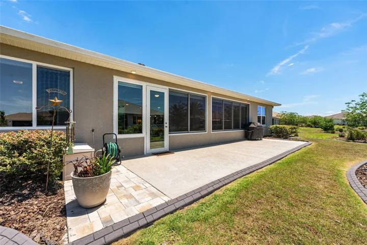 Expansive outdoor patio with soffit lighting, gas line for the grill, and included grill, all overlooking the landscaped backyard.