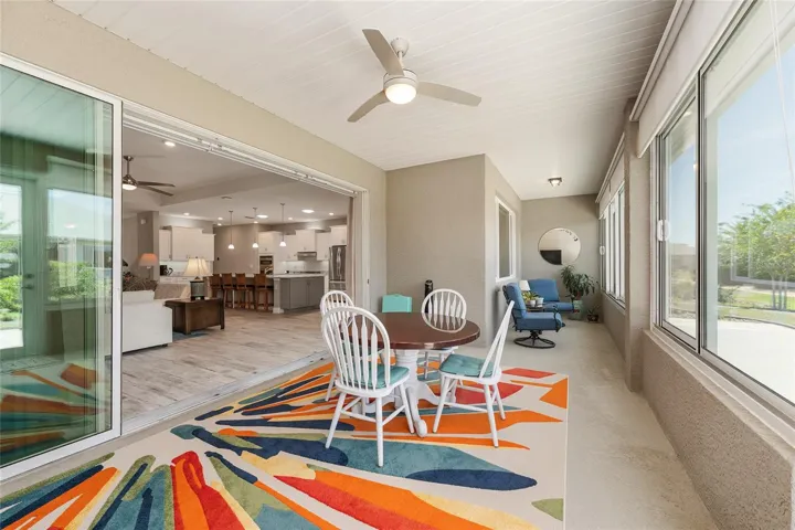 Inviting enclosed lanai with a seamless level transition from the great room, painted walls, 24-inch knee wall, ceiling fan with lighting, GFCI outlet, and custom solar shades.