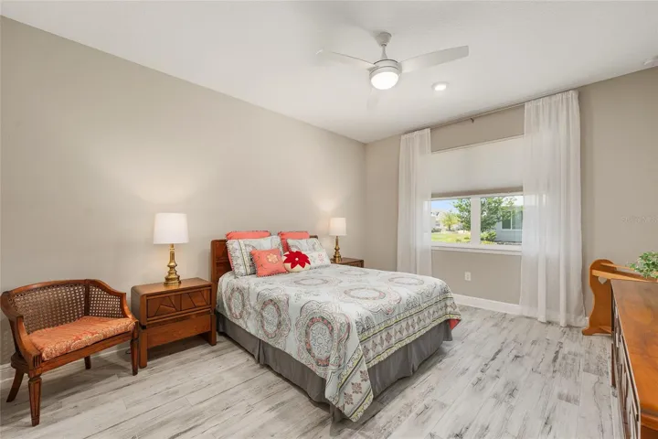Second primary suite featuring ceramic plank flooring, ceiling fan with light, neutral finishes, and a comfortable ensuite-style layout for guests or multi-generational living.