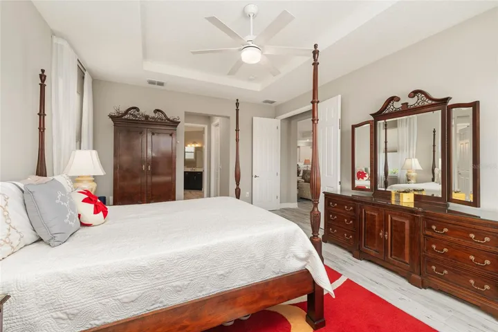 First primary ensuite with double-door entry, tray ceiling, ceramic plank flooring, and great natural light.