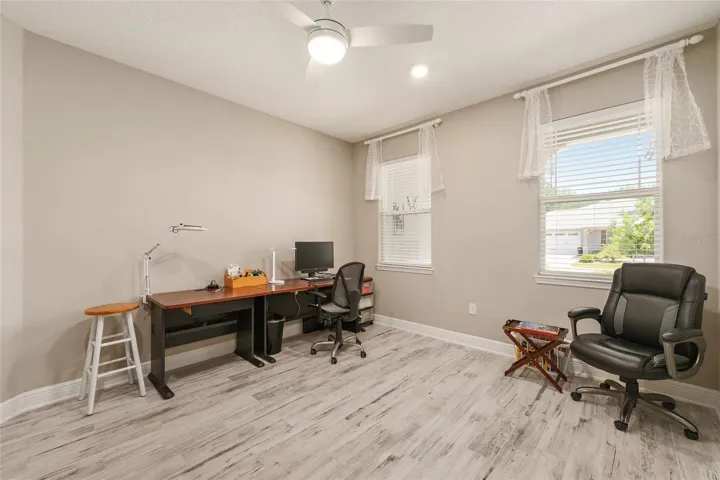 Versatile flex room with front-facing windows, ceramic plank flooring, recessed lighting, ceiling fan with lighting, and neutral finishes—perfect for an office, sitting room, or hobby space.