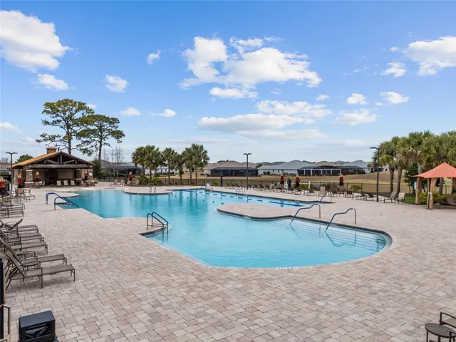 Candler Hills resort-style pool featuring swim lap lanes, beach entry, spacious pool deck, and clubhouse views—perfect for exercise, relaxation, and enjoying the Florida lifestyle.
