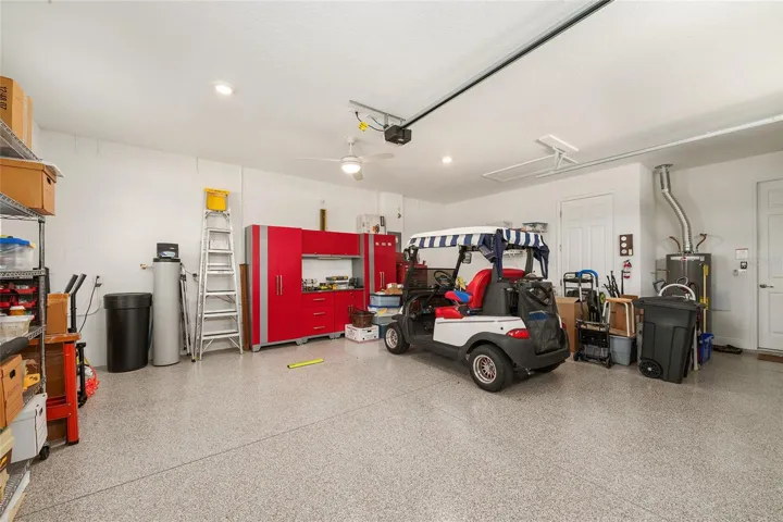 Spacious two-car garage with epoxy flooring, recessed lighting, and a ceiling fan with light.
