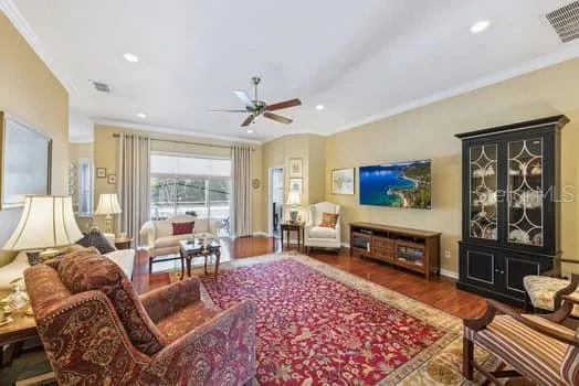 Large Living room with laminate flooring, crown molding and even mounted TV stays.