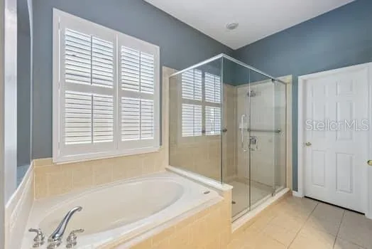 Large Primary Bathroom with garden tub, plantation shutters. a large separate shower as well as double sink vanity and separate commode area.  The door leads to a large walk-in closet