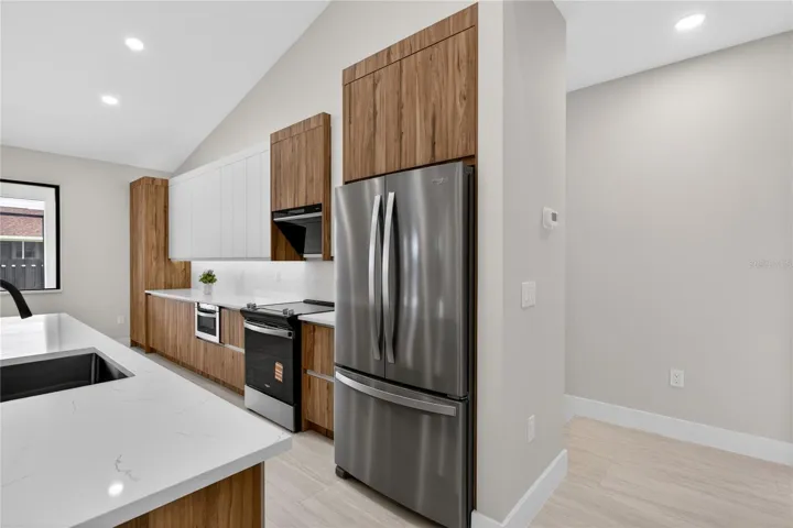 Crisp QUARTZ COUNTERTOPS & matching FULL BACKSPLASH complement modern palette, while UNDER-CABINET LED LIGHTING enhances the bright, open feel.