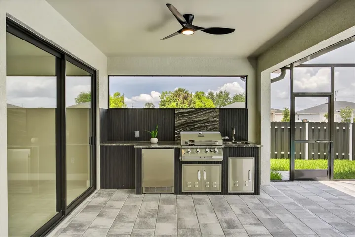 FULLY EQUIPED OUTDOOR KITCHEN w/ BUILT-IN stainless steel BBQ GRILL, SINK, BEVERAGE REFRIGERATOR, GRANITE COUNTERTOPS & MODERN BACKSPLASH, ideal for OUTDOOR DINING & ENTERTAINING!