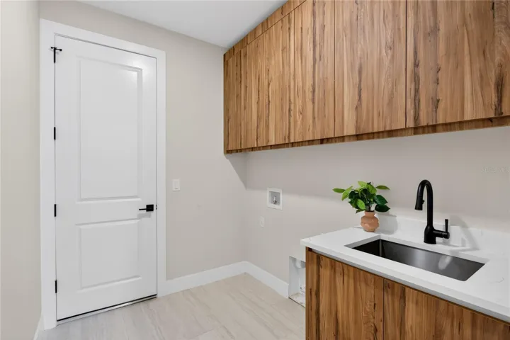 LAUNDRY with laundry tub and custom cabinetry, 3-CAR GARAGE & long-lasting METAL ROOF complete HOMES' FUNCTIONAL FEATURES.